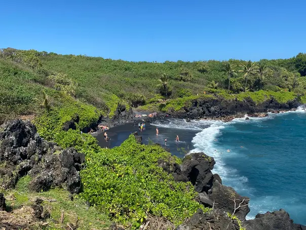 Black-sand beach and blue Pacific water on the Hana and Back tour