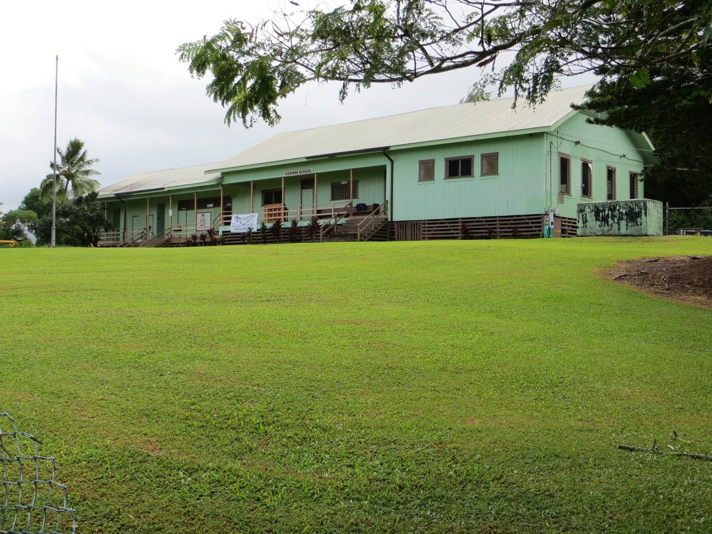 The long, small-scale vernacular wooden Keʻanae School building behind a green lawn