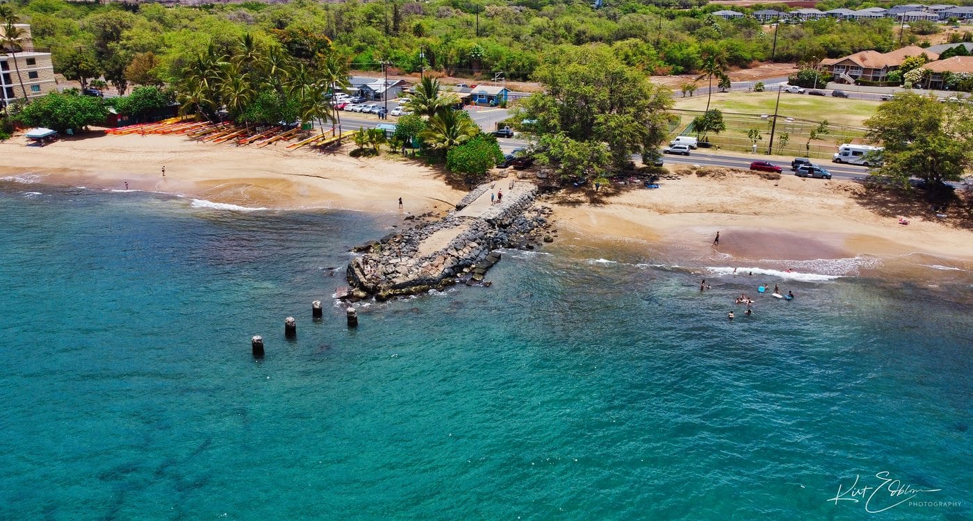 Aerial view of the rocky remains of old Kīhei Wharf extending from the beach
