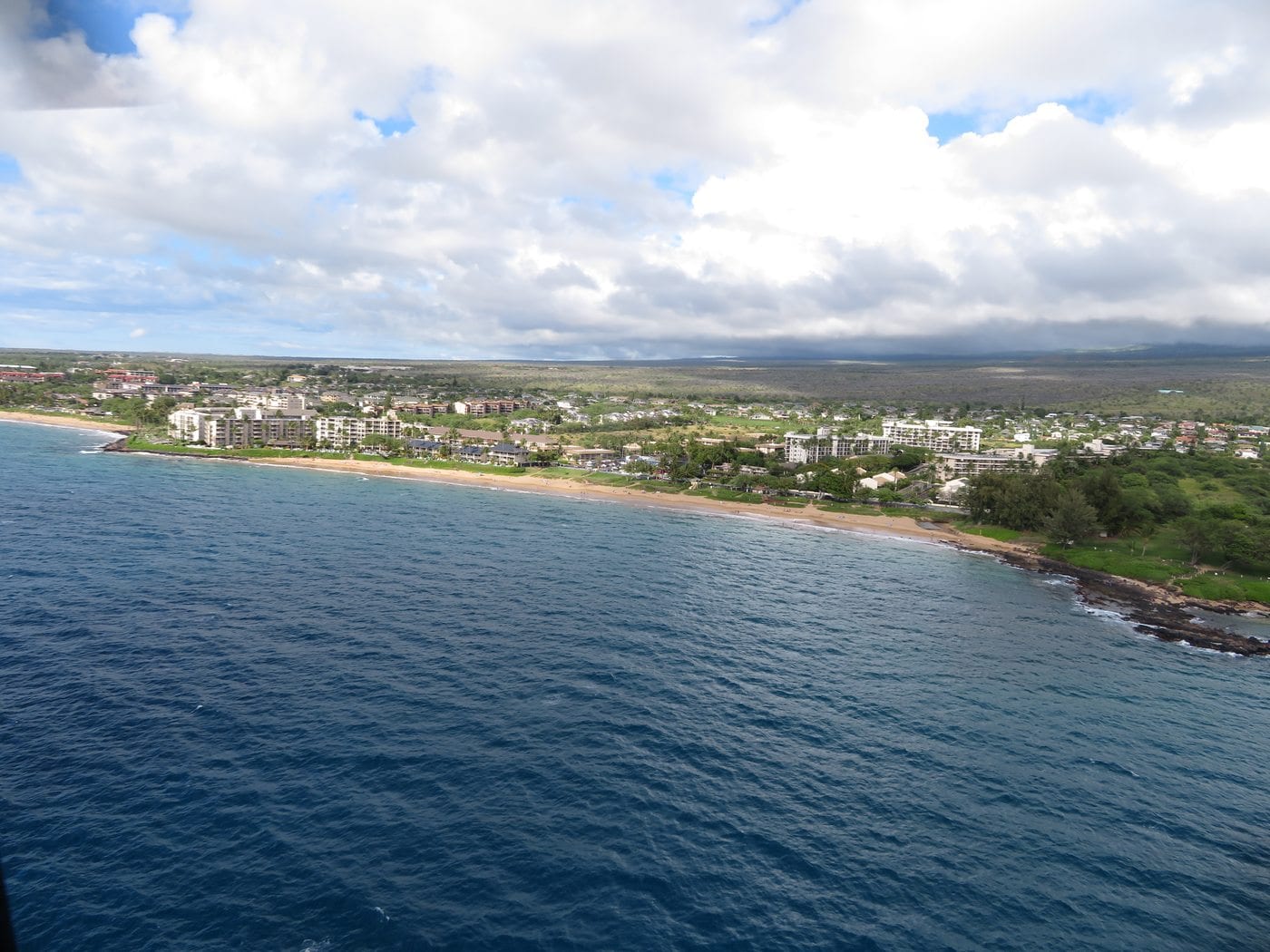 Aerial view of Kīhei’s shoreline, condominiums, neighborhoods, and dry inland plain