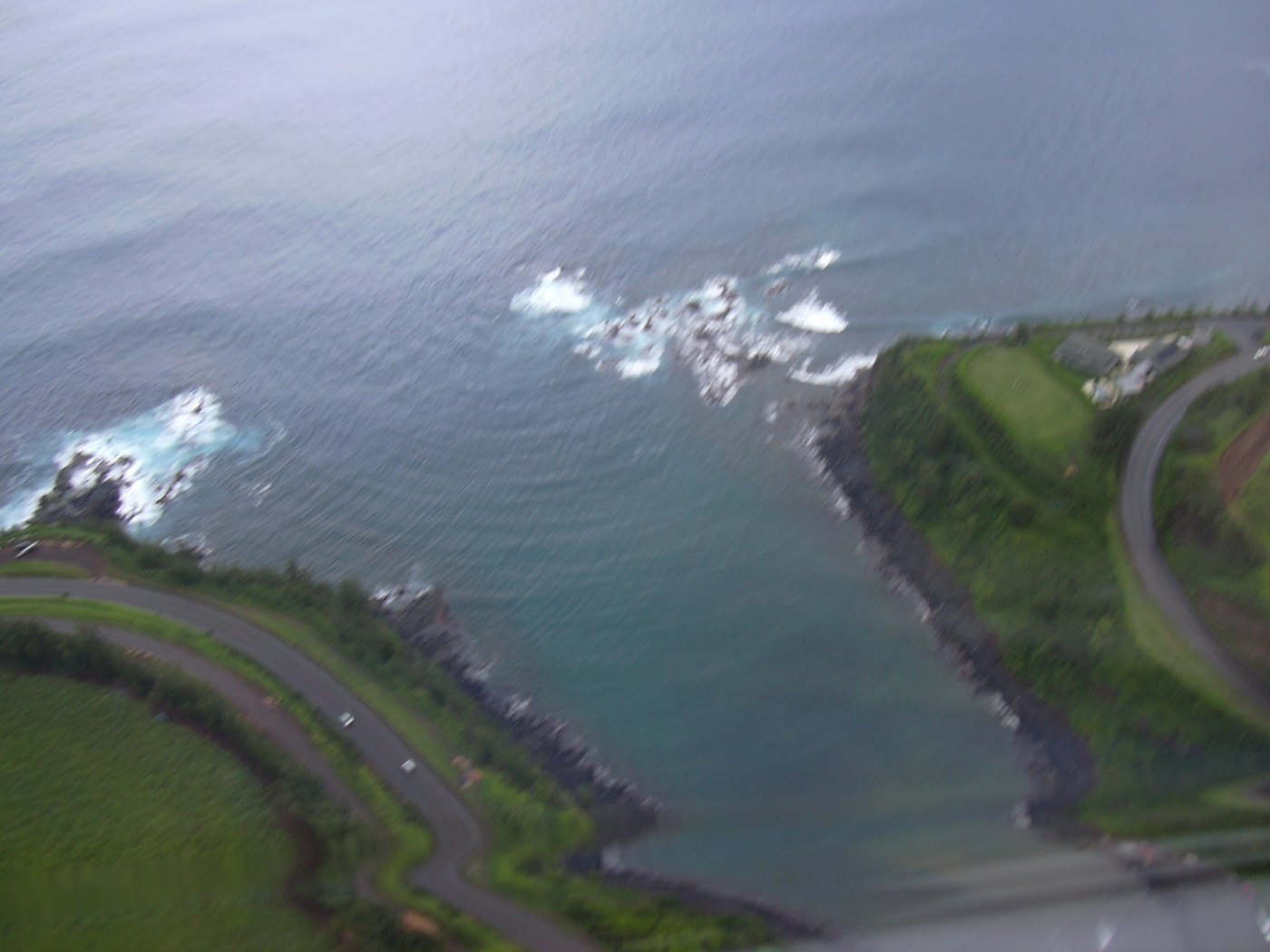 Aerial view of the narrow entrance, road, and surf at Māliko Bay