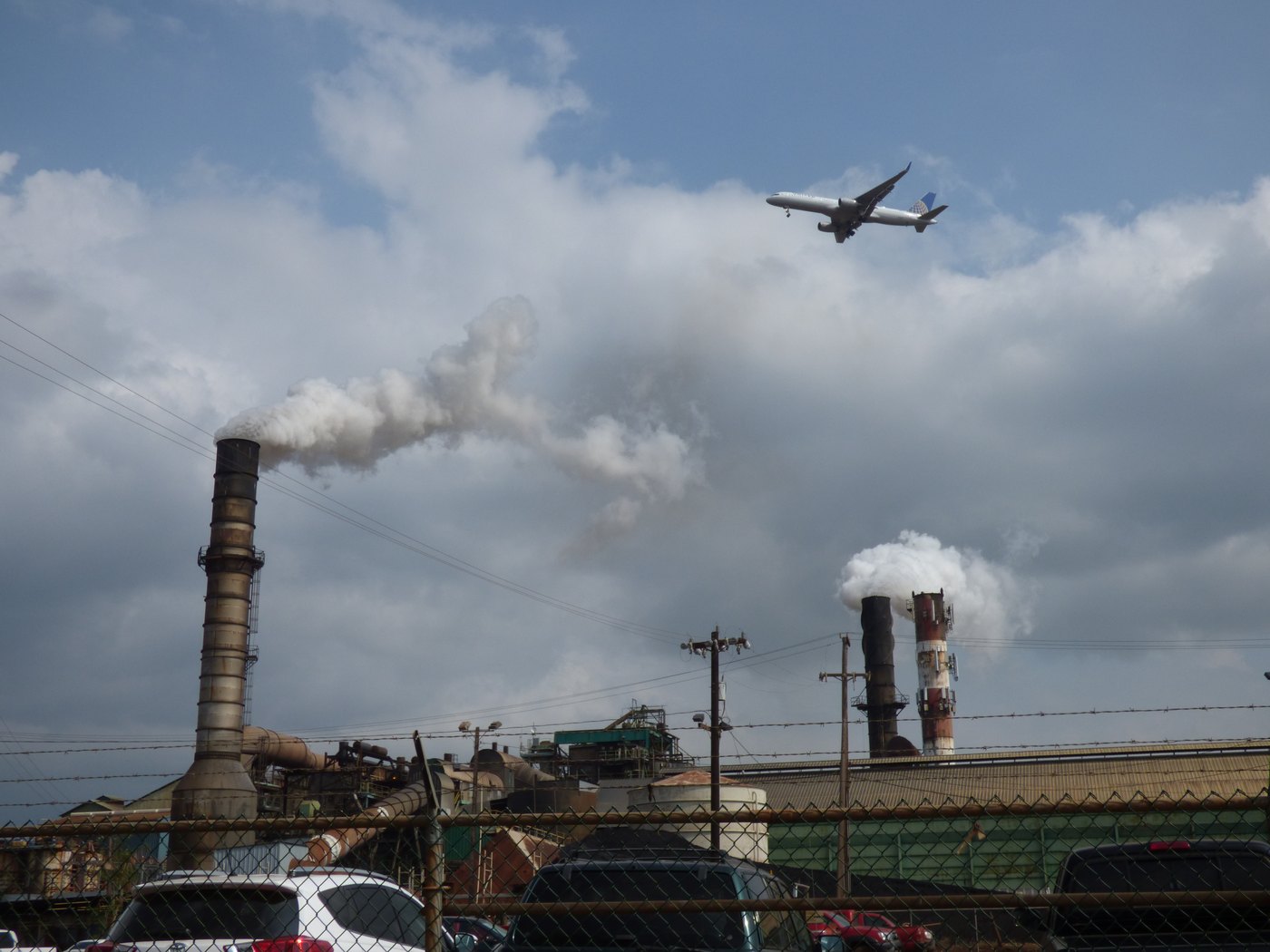 Passenger airplane descending above the Puʻunēnē sugar mill smokestacks in 2016